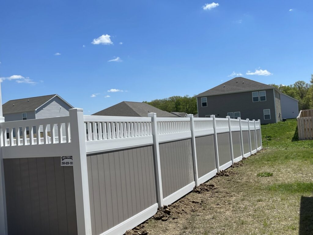 A modern two-tone vinyl fence in grey and white, professionally installed in a residential backyard by NBBJ Fence LLC in Bluffton, IN.