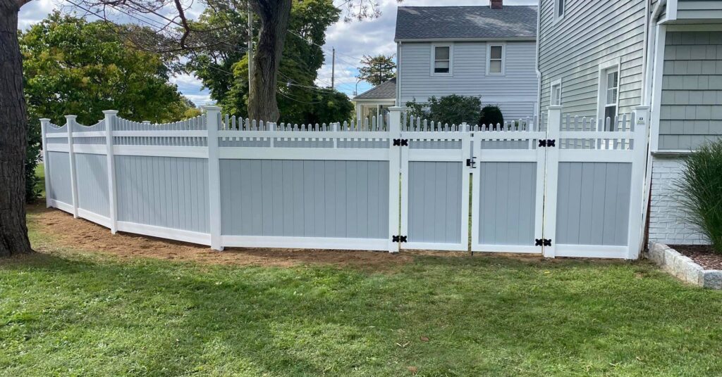 Two-tone grey and white vinyl fence with a gate installed in a backyard by Select Fence & Guardrail in North Haven, CT.