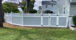 Two-tone grey and white vinyl fence with a gate installed in a backyard by Select Fence & Guardrail in North Haven, CT.