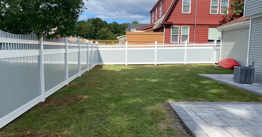 Two-tone grey and white vinyl privacy fence installed in a backyard by Select Fence & Guardrail in North Haven, CT.
