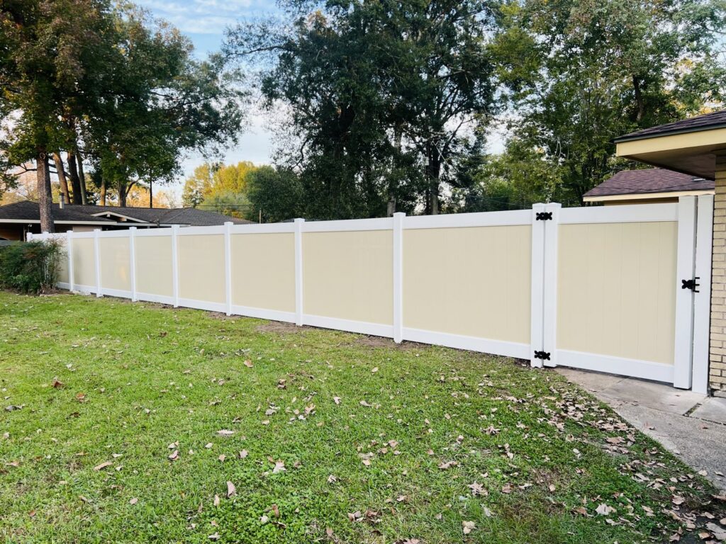 A modern two-tone vinyl privacy fence with a gate installed in a residential backyard by Capitol Fencing in Baton Rouge, LA.