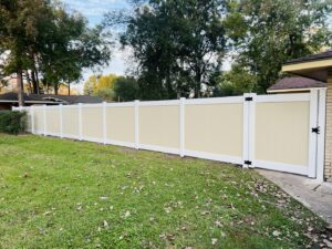 A modern two-tone vinyl privacy fence with a gate installed in a residential backyard by Capitol Fencing in Baton Rouge, LA.