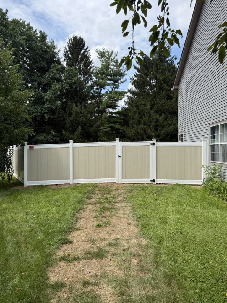 A stylish two-tone vinyl privacy fence with a gate, installed by Hoplite Services in Indianapolis, IN.