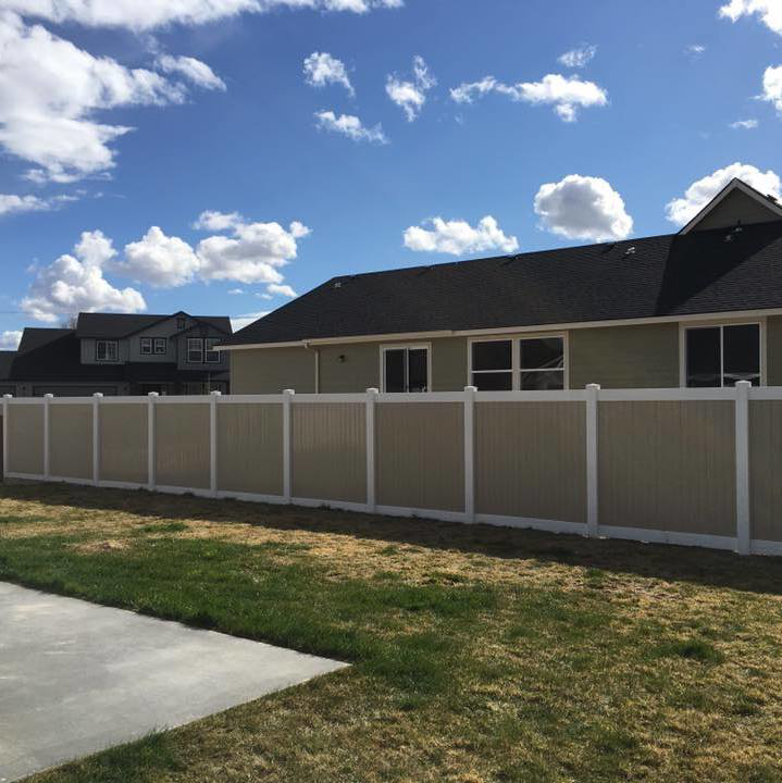 A long, newly installed two-tone vinyl privacy fence in a residential backyard by Double A Fence LLC in Boise, ID.