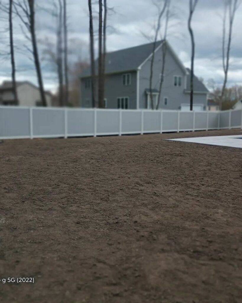 A stylish two-tone white and grey vinyl privacy fence installed by Reilly Fence Inc in Cranston, RI.