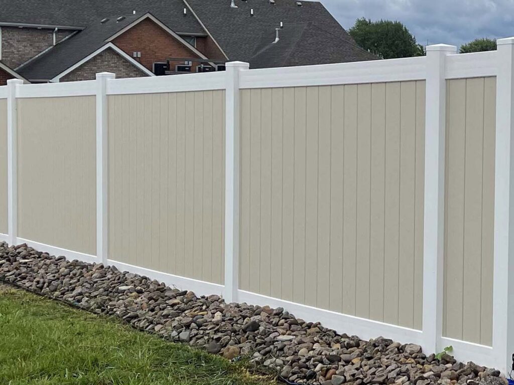 A modern two-tone vinyl privacy fence with decorative rocks installed by Frontier Fence LLC Bowling Green,Ky