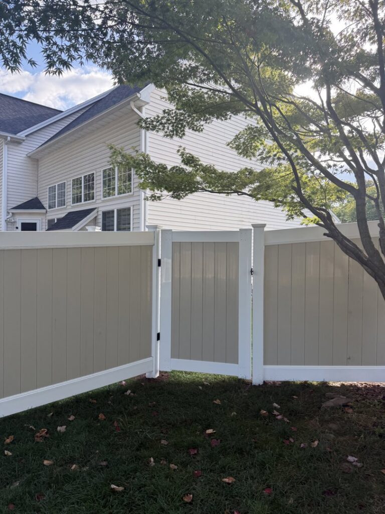 A stylish two-tone vinyl privacy fence with a matching gate installed by Camp Carlson Fencing in Rochester, NY.