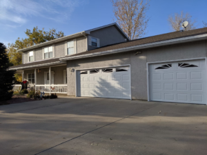Two white carriage-style garage doors installed on a home by Southern Colorado Garage Door in Pueblo, CO.