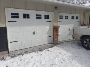 Two newly installed white garage doors with windows and decorative hardware by Black Forest Door Repair in Colorado Springs, CO.