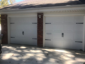 Two newly installed white garage doors with decorative hardware by Tulsa Garage Door Doctor LLC in Tulsa, OK