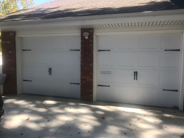 Two newly installed white garage doors with decorative hardware by Tulsa Garage Door Doctor LLC in Tulsa, OK