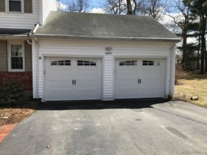 Two white garage doors with decorative hardware and top windows installed by Snowbird Garage Doors Company in Worcester, MA.