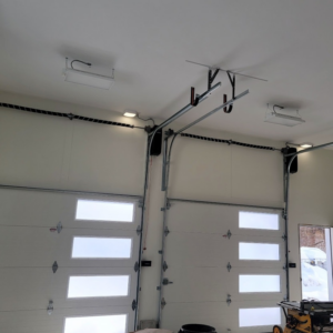Two newly installed white garage doors with openers and tracks visible from the interior, by Southcoast Overhead Door & Services in Fall River, MA.