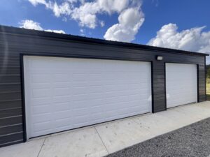 Two pristine white garage doors installed on a modern metal building by Knox Garage Door Service LLC in Knoxville, TN.