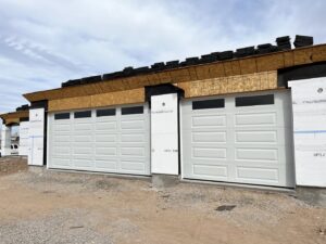 Two white garage doors with windows installed on a new construction home by Anew Garage by Jon's Garages in Surprise, AZ.