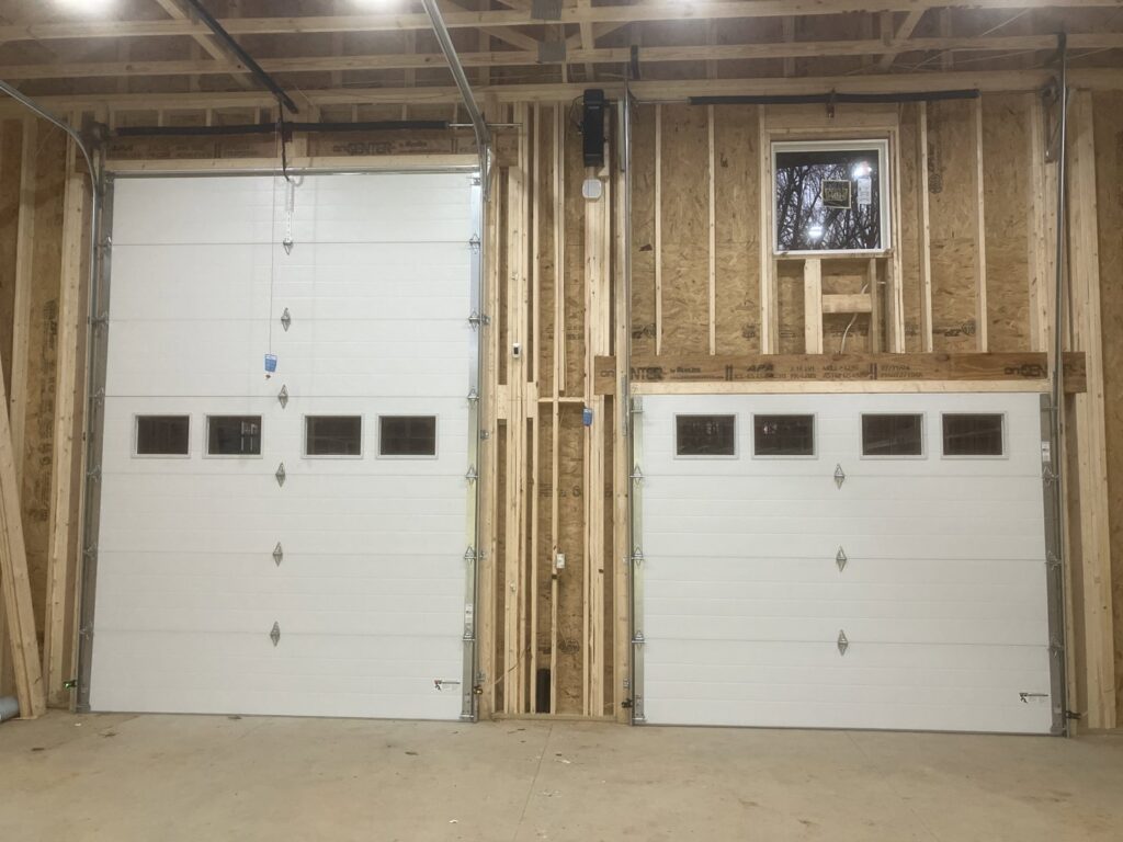 Two white garage doors with windows during a new installation by Precision Door Service of Huntsville, AL.