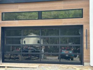 Two white garage doors with decorative hardware and stone facade on a newly built home by Skylift Garage Doors - Knoxville, TN