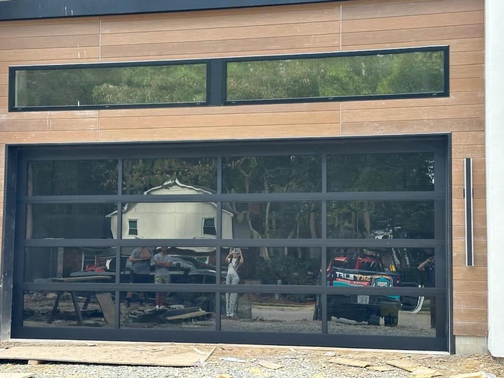 Two white garage doors with decorative hardware and stone facade on a newly built home by Skylift Garage Doors - Knoxville, TN