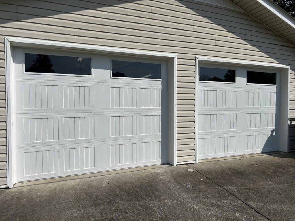 Two white garage doors with top windows installed on a residential home by Precision Door Service of Huntsville, AL.