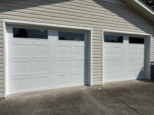 Two white garage doors with top windows installed on a residential home by Precision Door Service of Huntsville, AL.