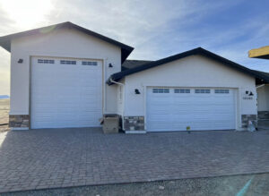 Two white panel garage doors with windows installed on a new construction home by Sonoran Garage Doors in Mesa, AZ