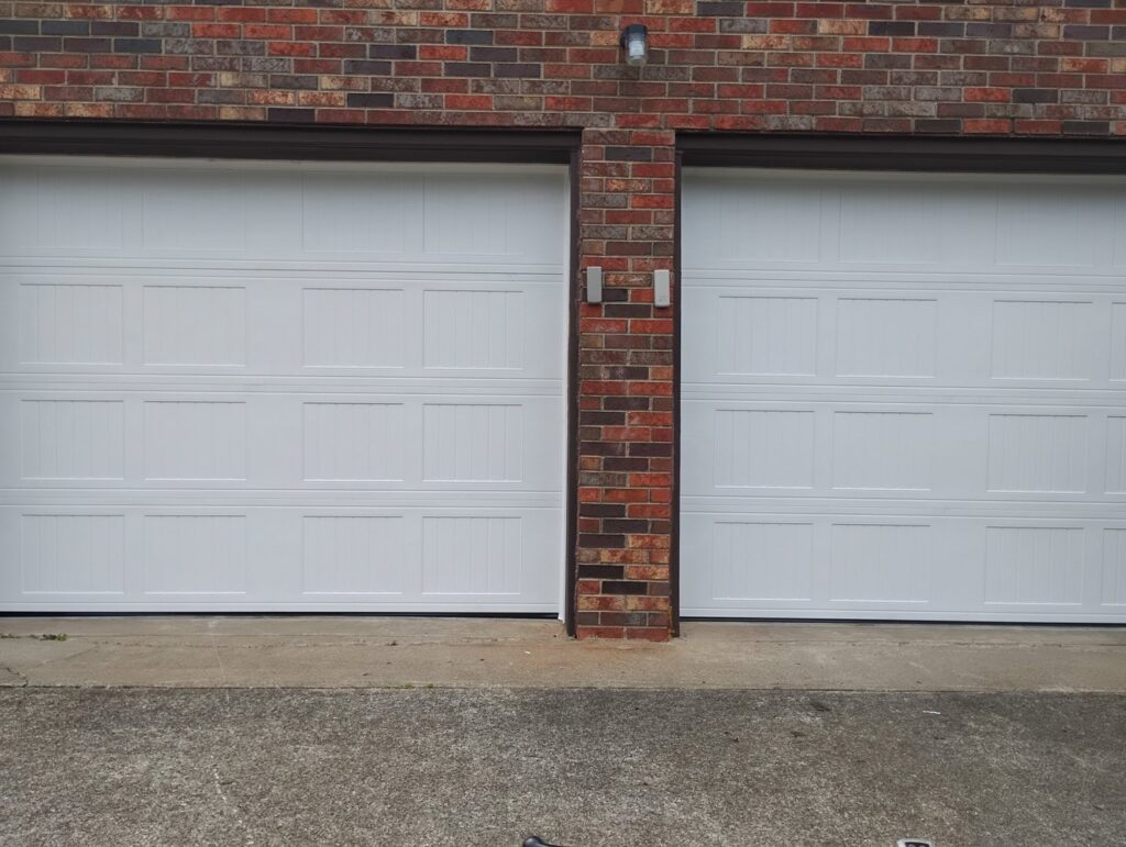 Two white panel garage doors installed on a brick residential building by Swift Garage Door in Nashville, TN.