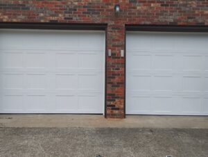 Two white panel garage doors installed on a brick residential building by Swift Garage Door in Nashville, TN.