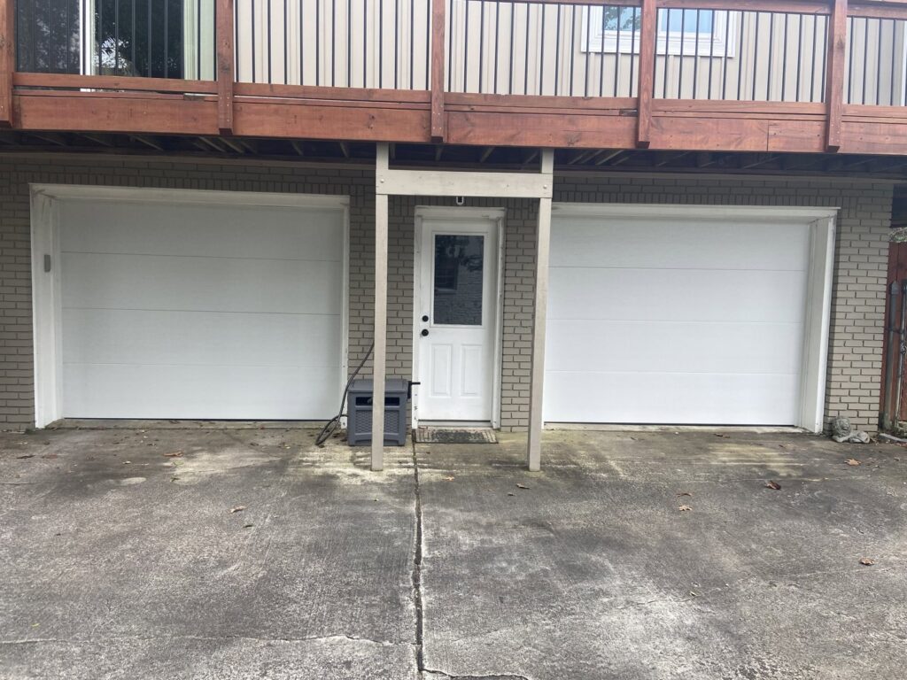 Two white residential garage doors installed below a deck by Magic City Door in Birmingham, AL.