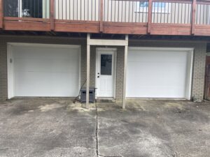 Two white residential garage doors installed below a deck by Magic City Door in Birmingham, AL.