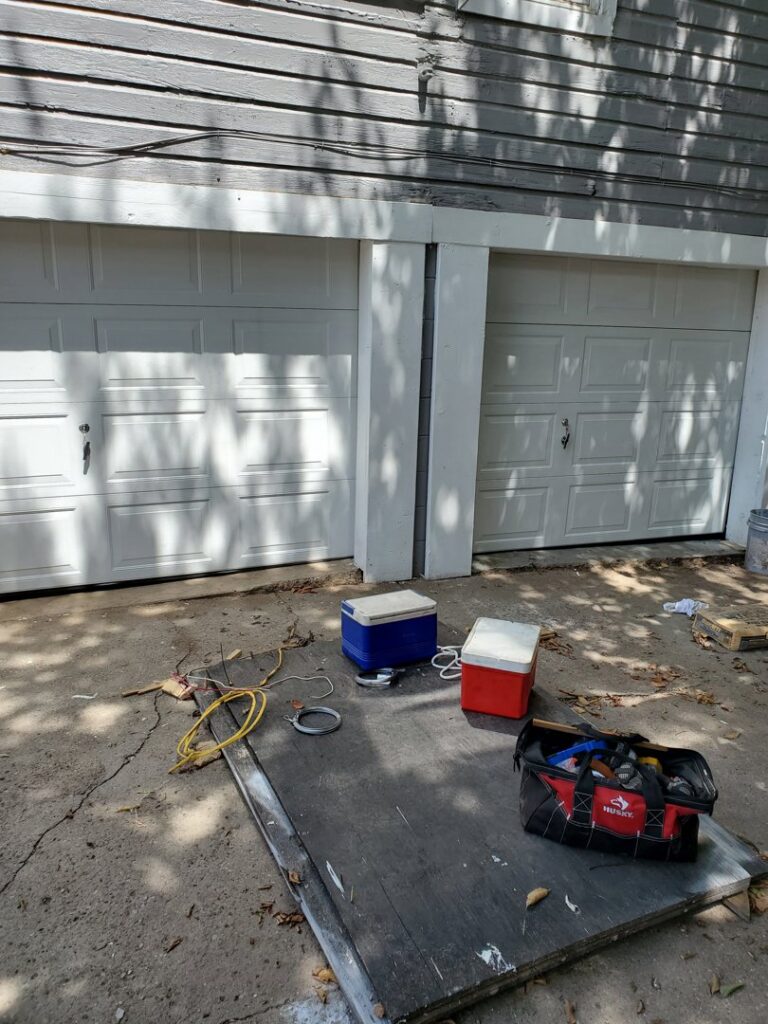 Two white residential garage doors with tools on the ground, indicating work by Garage Door Specialists Of Oklahoma Inc. in Midwest City, OK.