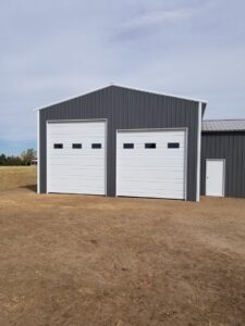 Two white sectional garage doors installed on a metal building by Colorado Garage Door Pro's in Denver, CO