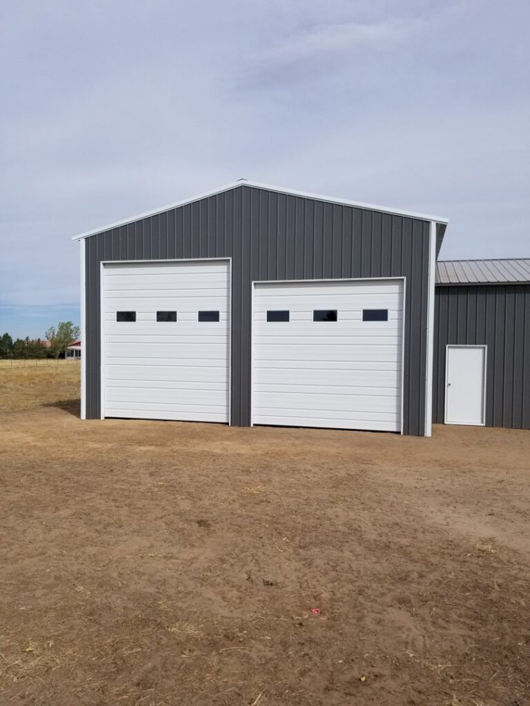 Two white sectional garage doors installed on a metal building by Colorado Garage Door Pro's in Denver, CO