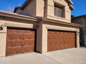 Two attractive wood-grain garage doors installed on a residential home by JT's Overhead Doors in Gilbert, AZ.
