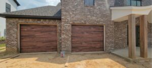Two new wood-grain garage doors installed on a modern brick house by Geaux Overhead Door in West Monroe, LA.