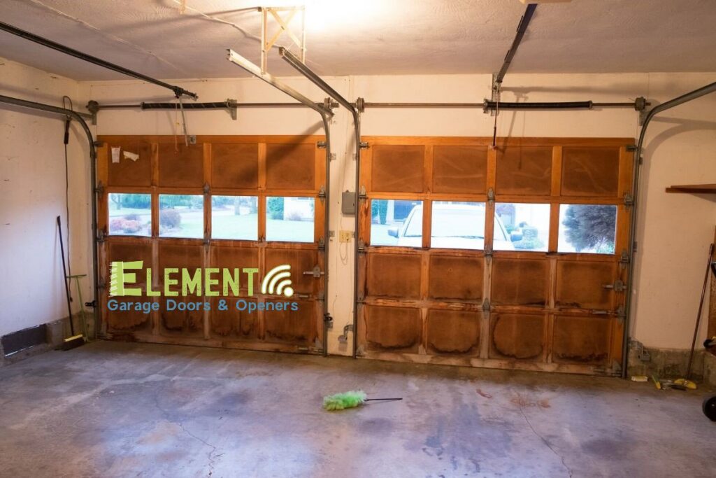 Interior view of a garage with two wooden panel garage doors installed by Element Garage Door Repair Of Portland, OR