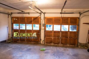 Interior view of a garage with two wooden panel garage doors installed by Element Garage Door Repair Of Portland, OR