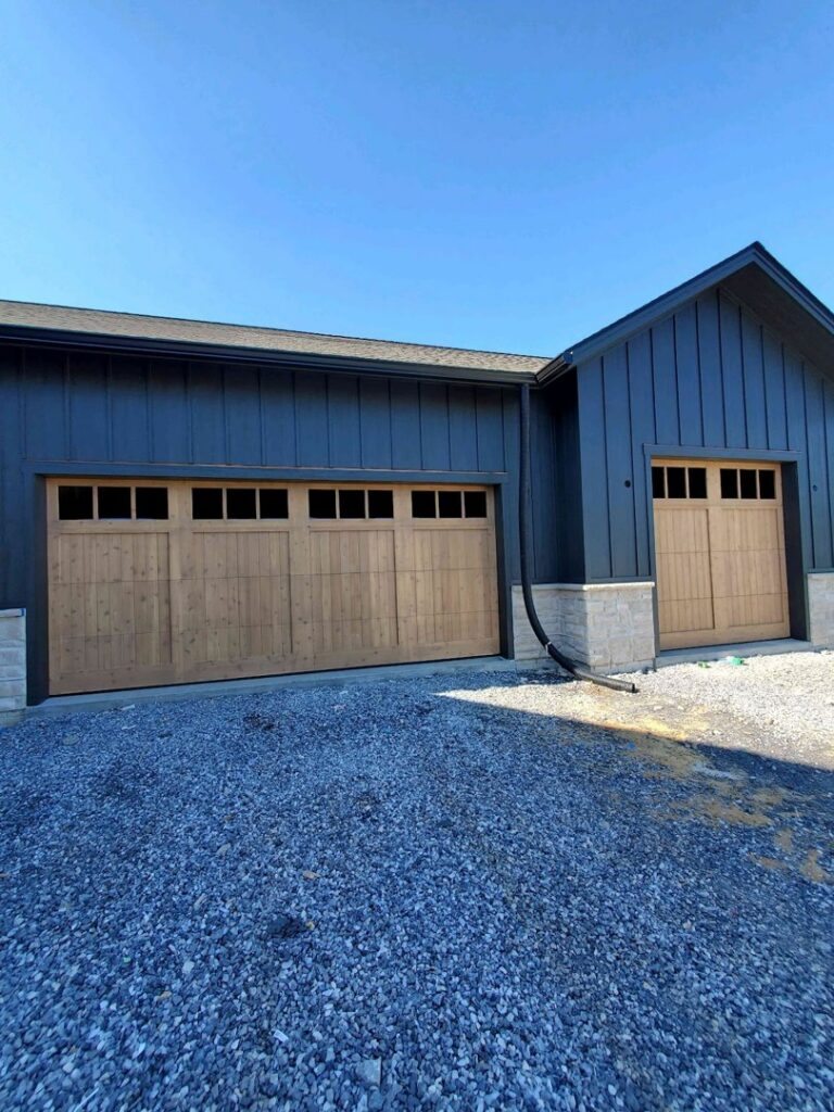 Two newly installed wooden-style garage doors with windows on a modern building by Door Serv Pro in Inwood, WV.
