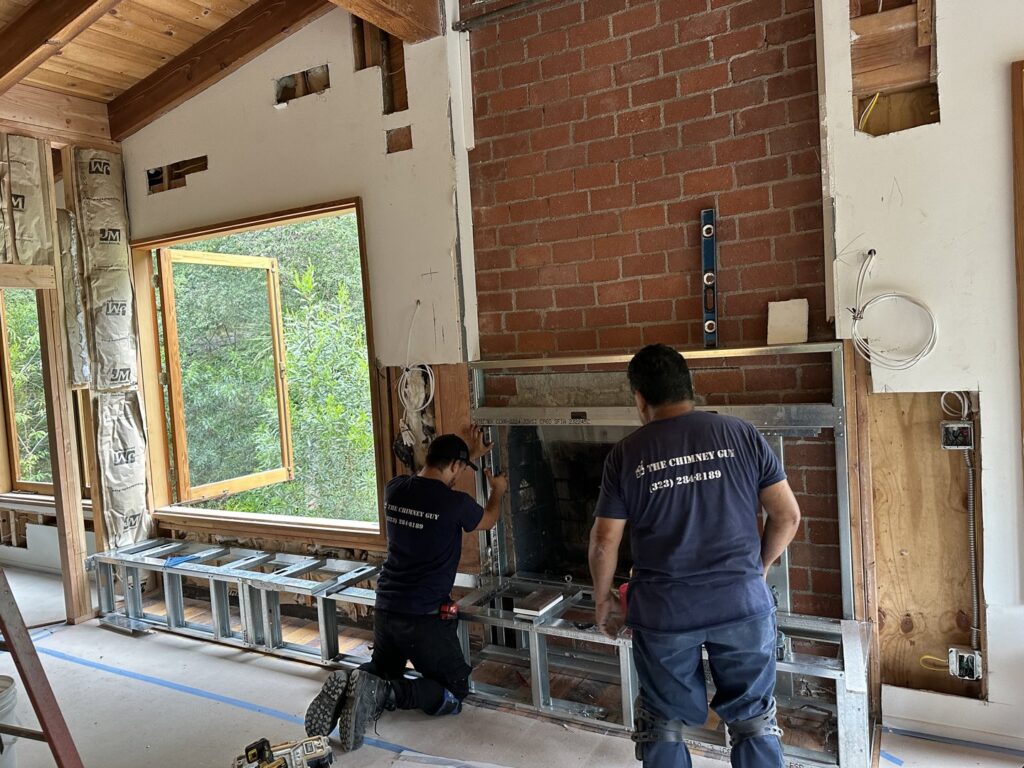 Two workers from The Chimney Guy installing a new fireplace insert and framing in a home in Los Angeles, CA.
