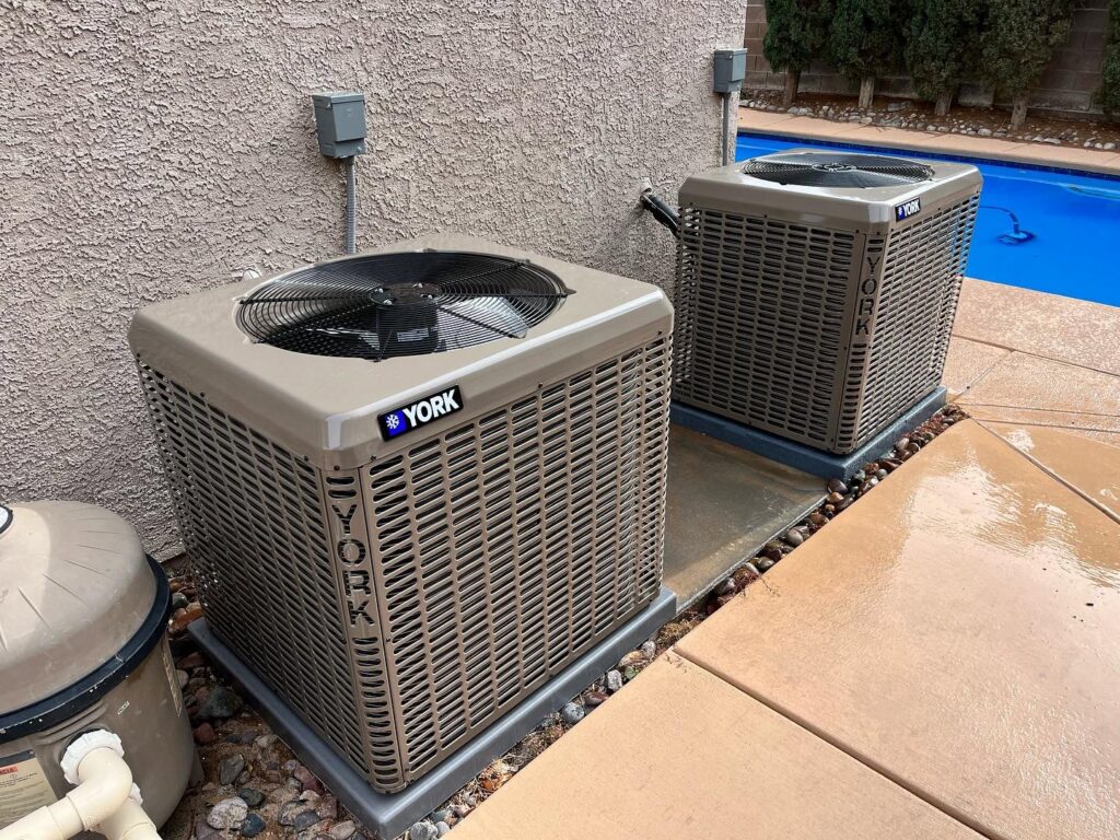 Two York outdoor air conditioning units installed next to a swimming pool by The Heating & Cooling Company LLC in Las Vegas, NV.