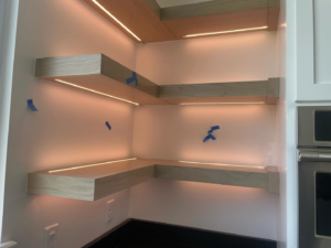 Custom under-shelf LED lighting and electrical outlets installed by Outlaw Electric in a modern kitchen in Tulsa, OK.