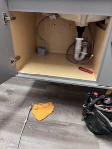 Electrician tools and an electrical box under a sink, indicating electrical work by Quistian Lighting in Arlington, TX