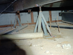 An under-structure area with support jacks and pipes, often inspected for pests by Zip Zap Termite & Pest Control in Mesa, AZ