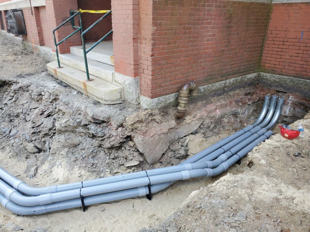 Underground electrical conduits entering a building foundation, installed by Icon West Corporation Electrical Contractors in Springfield, MA.