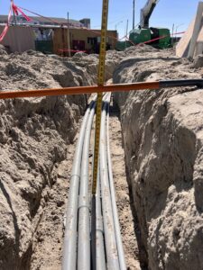 Underground electrical conduits being installed in a trench, measured for depth by Krakkom Electric in Sunrise, FL.