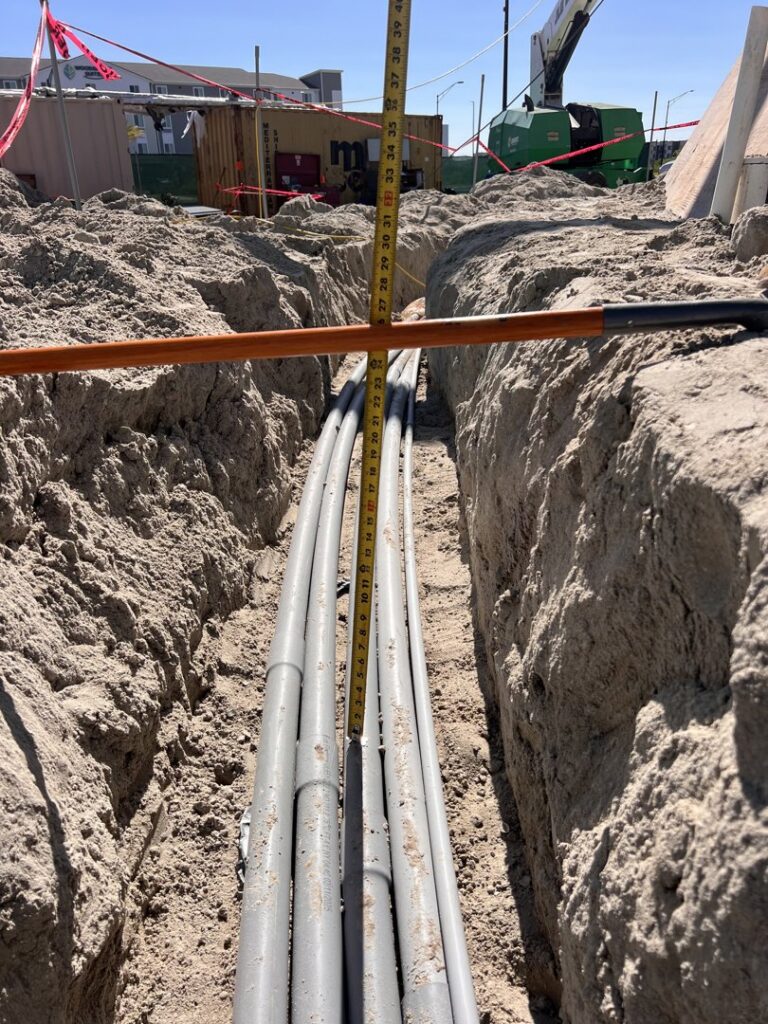 Underground electrical conduits being installed in a trench, measured for depth by Krakkom Electric in Sunrise, FL.