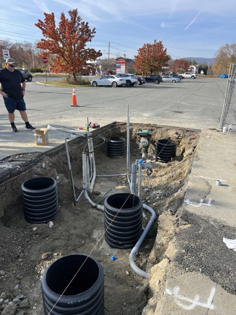An excavated trench showing underground electrical conduits and utility pipes being installed by Peeler Electric Light & Power in Merrimack, NH.