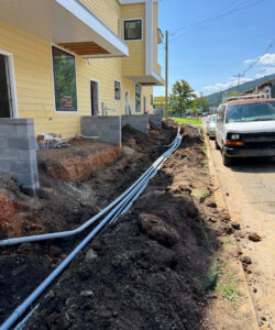 Underground electrical conduit pipes being installed next to a building by Raschke & Sons Electric in Chattanooga, TN
