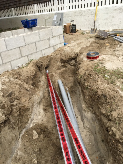 Underground electrical conduit installation with caution tape in a trench by RTF Electric LLC in Toms River, NJ.
