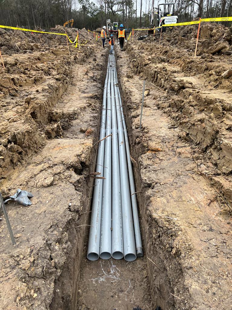 Underground electrical conduits being installed in a trench at a construction site by Solution Electric in Houston, TX.