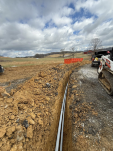 Two grey underground electrical conduits being laid in a trench by Power House Electrical LLC in Johnson City, TN